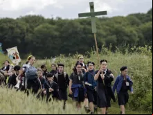 Jovens seguram cruzes ao chegarem para a missa na tradicional peregrinação de Pentecostes de Paris a Chartres, em Sonchamp, perto de Paris, no último domingo (8).